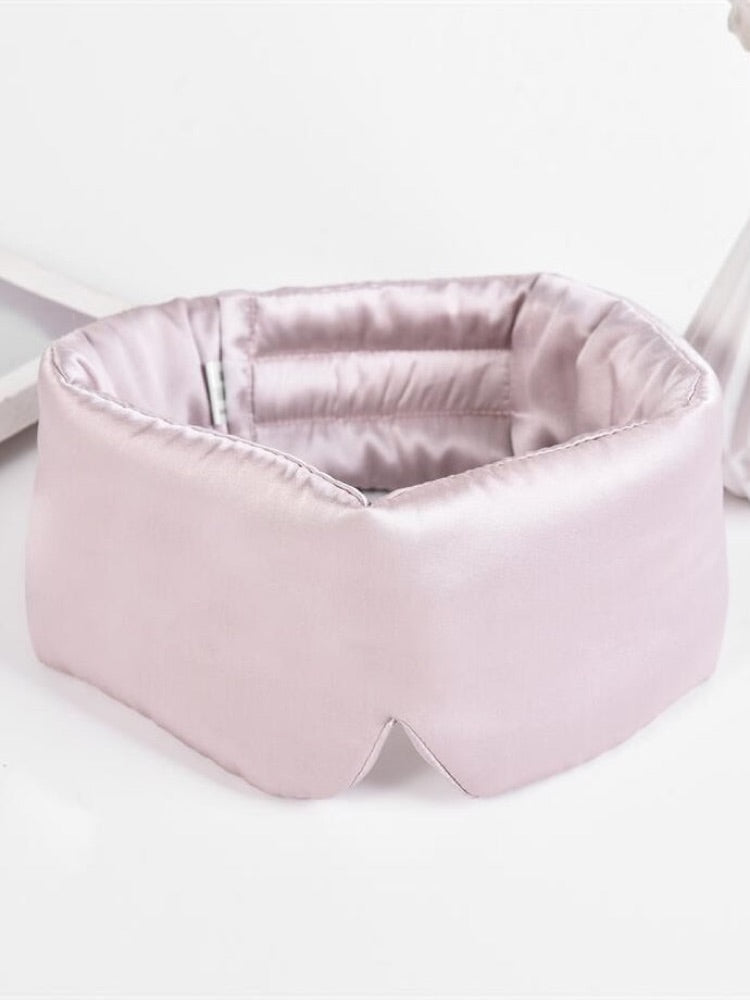 Pastel pink SilkRest silk sleep mask laid flat, showing the wide padded shape