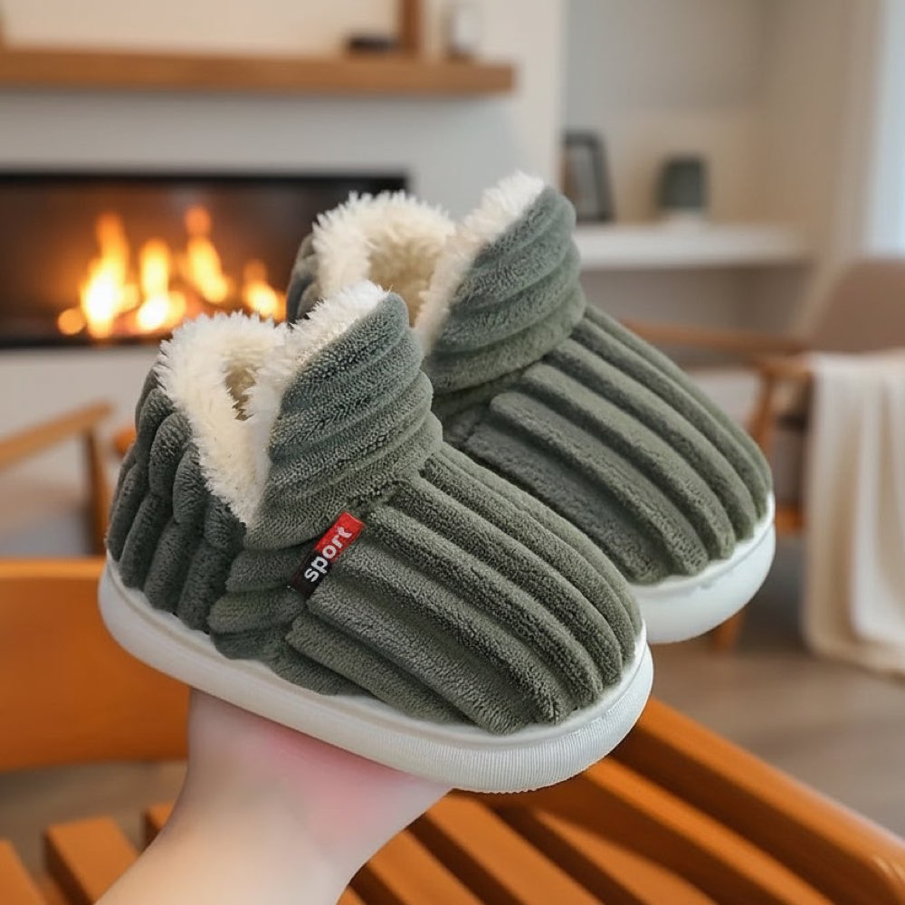 Green WarmStep winter slippers held in front of a fireplace