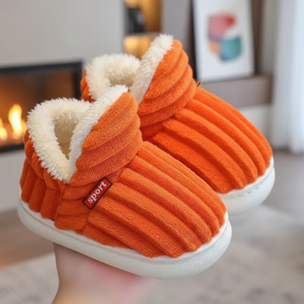 Orange WarmStep winter slippers in front of a fireplace